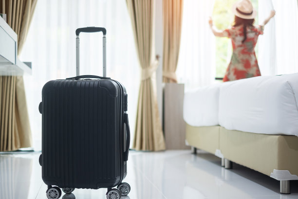 行李在现代酒店房间与快乐的年轻成年女性放松近窗口，亚洲女游客看着美丽的自然景色。时间去旅行，放松，旅行，旅行和度假的概念图片下载