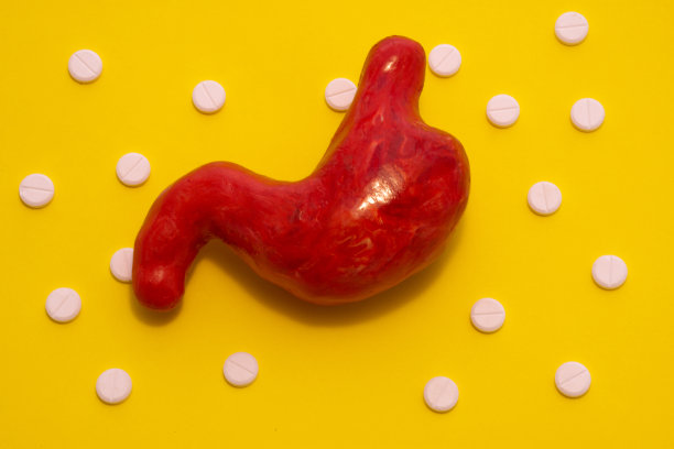 胃的解剖图形，活体器官的形状相同，是在黄色的背景周围环绕着白色的丸子，成分波尔卡圆点点缀。用于胃肠病学的照片，概念治疗图片下载