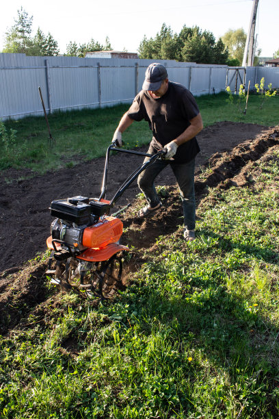 一个人在田里工作——穿着工作服的犁头在滴落着马达图片下载