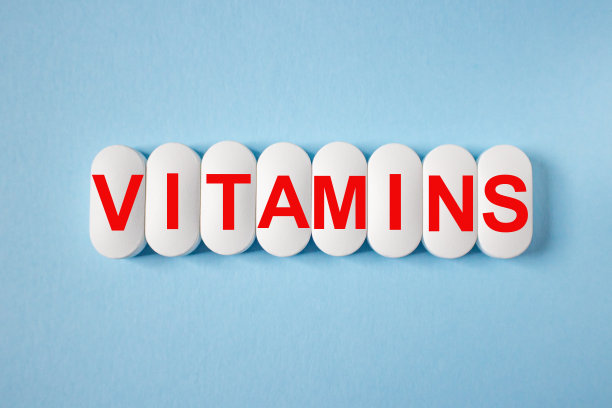 “维生素”这个词是用红色的字母写在蓝色背景的白色药片上的。强免疫力理念，预防冠状病毒，疾病养生。图片下载