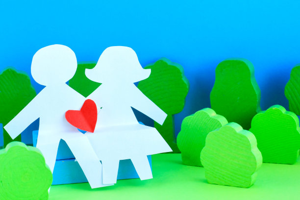 剪影，在明亮的绿色和蓝色的背景上从纸上剪下的情侣形象。情人节的概念，婚礼，传统的异性恋家庭。图片下载