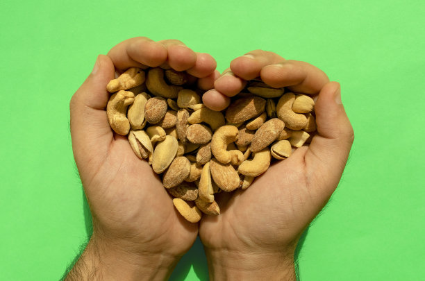 男人手中的混合坚果，构成心形图片下载