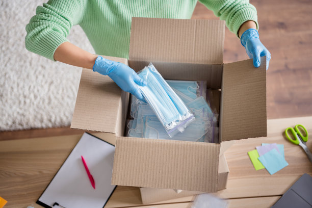 高角度查看裁剪照片商务女士整理脸部医疗口罩大盒子免费送货检查防毒防毒防毒口罩拉链袋寄包裹到客户家庭办公室室内图片下载