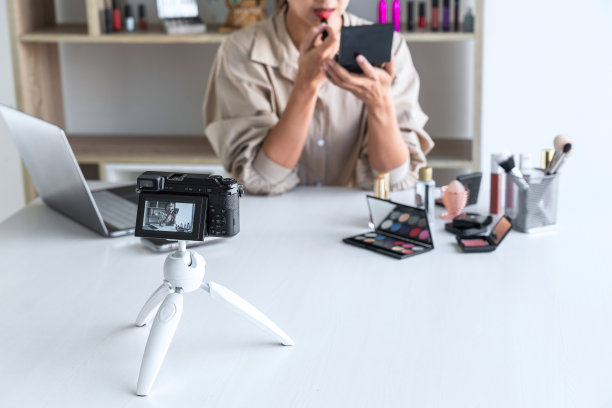 快乐微笑优雅的女子博主在摄像头屏幕上展示了目前的化妆教程美容化妆品评论产品，并对社交网络在线教学进行直播视频博客图片下载