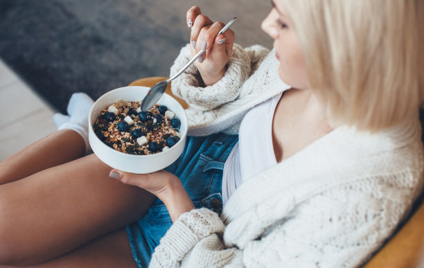 上面的照片，一个金发白种人妇女吃谷物和水果图片下载