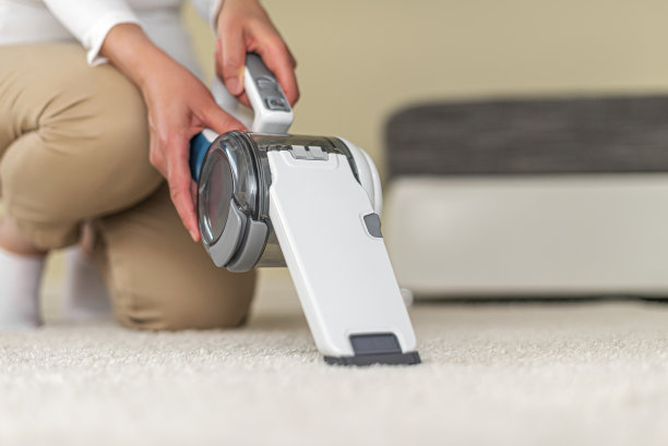 一个妇女在用手提式吸尘器打扫家具。图片下载