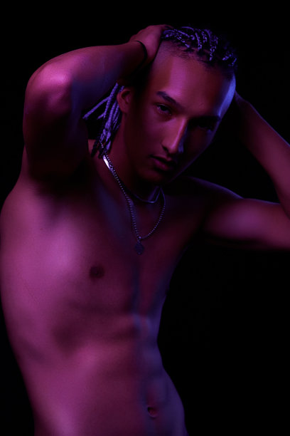 一个年轻的非洲人在工作室的肖像。时装男模特在五颜六色的霓虹灯下在黑色背景下摆姿势。艺术设计的概念。有选择性的重点图片下载