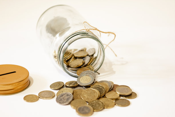 硬币放在透明的玻璃罐子里。素材图片