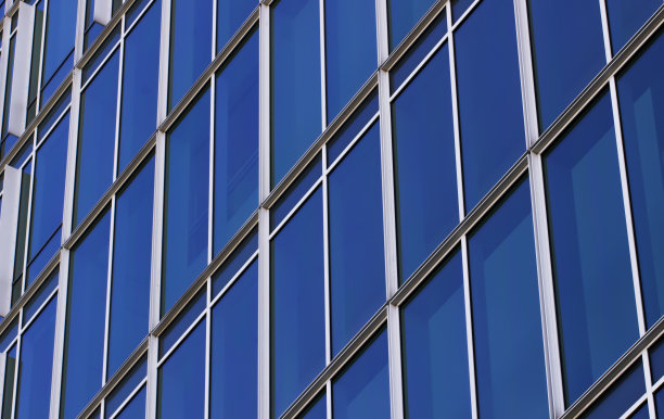 在特写中重复的蓝色窗户图案。现代办公大楼的外立面。图片下载