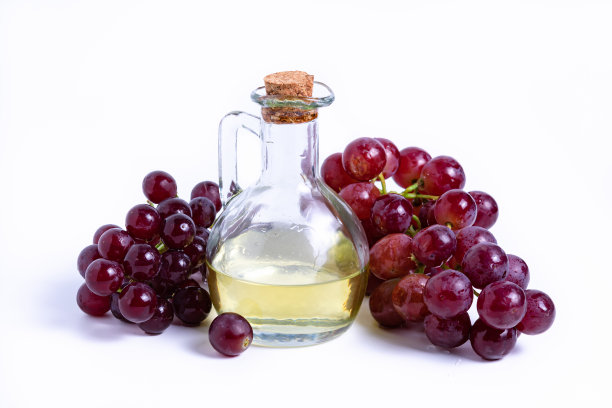 将一串葡萄和一瓶油分开放在白色的背景上图片下载