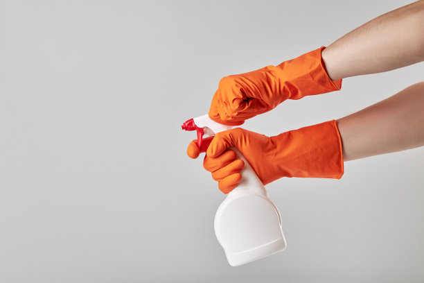 清洁人员佩戴橙色橡胶清洗手套，手持白色空白清洁喷雾。影棚拍摄。副本的空间。清洁和清洗最小化概念。图片下载