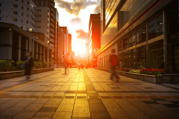 人们走在华尔街上，映衬着美丽的夕阳图片下载