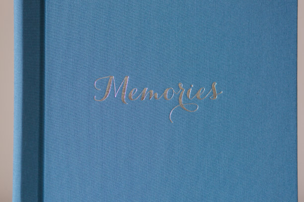 白色木桌上的相册。蓝色纺织婚礼相册与银压花图片下载