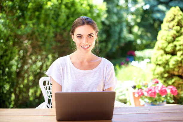 漂亮的年轻女子坐在户外书桌边使用笔记本电脑图片下载