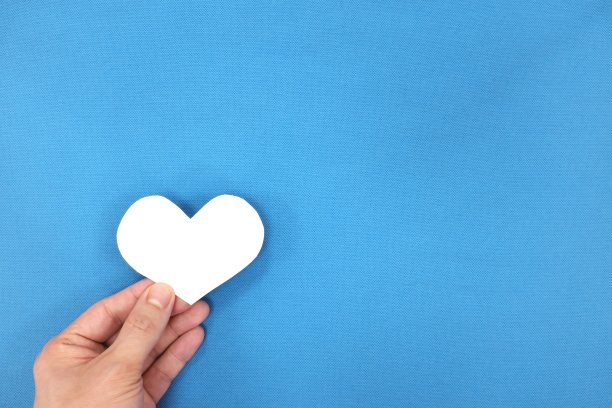 男性双手捧着白色的心形。慈善和善良的概念。顶部视图与复制空间。图片下载