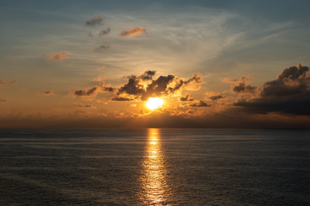 金色的日出或日落在海上，上面挂着一大片云彩和天空是美丽宁静的气氛感觉孤独。图片下载