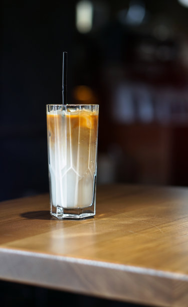 咖啡用玻璃杯喝。咖啡馆里深色背景上的拿铁。商业库存照片的设计图片下载