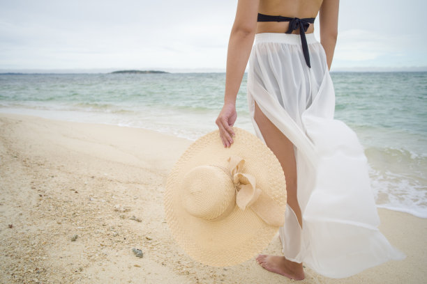 一名亚洲女子在晴朗的日子穿着比基尼和海帽在沙滩上图片下载