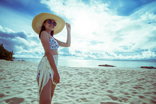 一名亚洲女子在晴朗的日子穿着比基尼和海帽在沙滩上图片下载