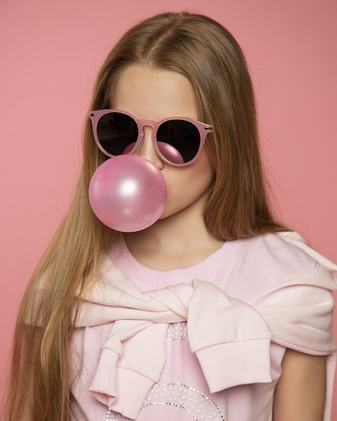 美丽有趣的10岁女孩戴着太阳镜和所有的粉红色制作泡泡糖在工作室的背景。概念特写照片广告胶，组织假期。积极的情绪图片下载