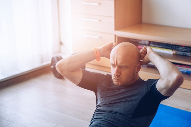 在家锻炼。男人在家里锻炼和做仰卧起坐。图片下载