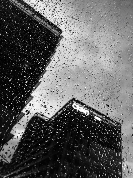 透过带有雨滴的玻璃看到的建筑物。图片下载