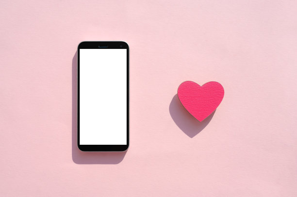 一款白色空白显示屏、心形手机位于粉色背景上。图片下载