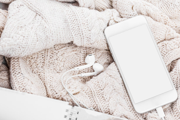 床上放毯子、杂志、智能手机和耳机图片下载
