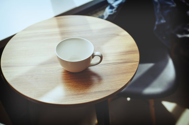 咖啡馆桌上空着的白杯子。晨光从窗户射进来。咖啡休息。模糊图像,选择聚焦图片下载