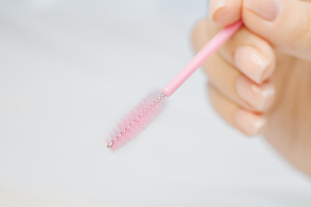 睫毛延长程序工具。女性手上有粉红色的镊子、钳子和刷子。延长睫毛的工具。人造睫毛。图片下载