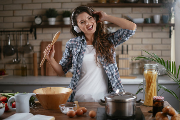 年轻女子一边在家做饭一边听音乐图片下载