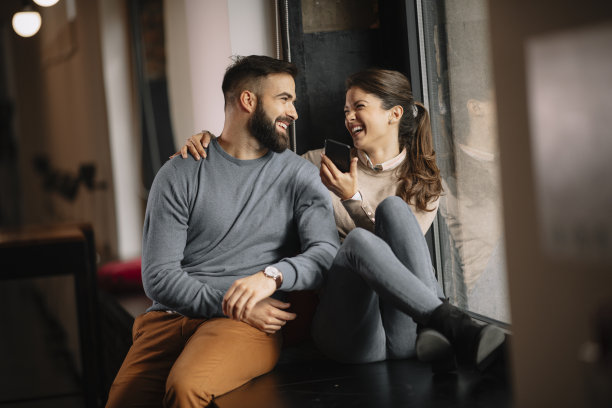 年轻的朋友坐在家里看手机上的照片。图片下载