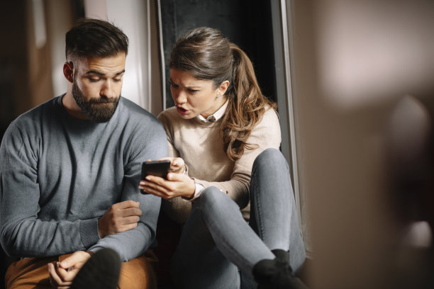 年轻的朋友坐在家里看手机上的照片。图片下载