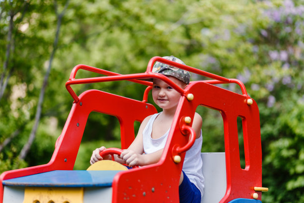 夏天，一个七岁的男孩坐在一辆木制的儿童汽车上。图片下载