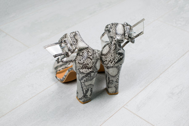 女人蛇皮皮鞋与高跟鞋在木制背景。图片下载