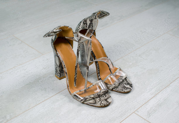 女人蛇皮皮鞋与高跟鞋在木制背景。图片下载