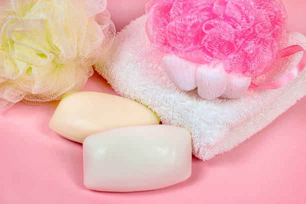 亮粉色肥皂和海绵，白色毛巾，玫瑰色背景。女性护肤品和卫生用品的概念图片下载