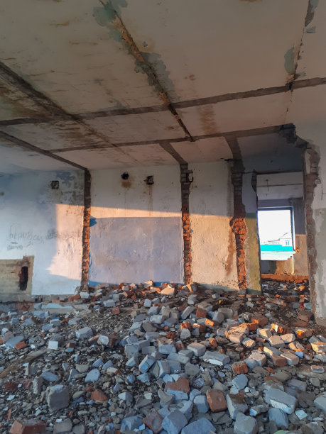 照片的一个废弃的房子从里面房间的地板上散落着粗糙的砖透过缺失的窗户明亮打破阳光的墙壁上画涂鸦图片下载