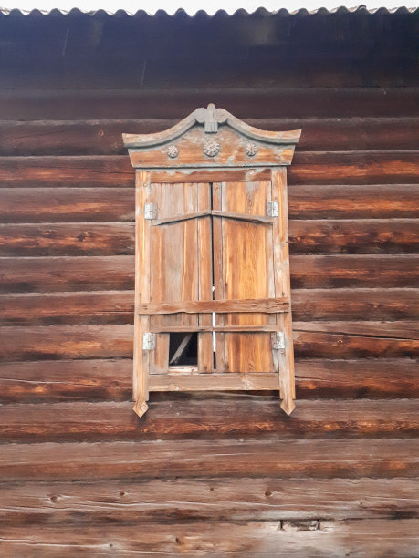 这是一个废弃的旧木屋的照片，俄罗斯的原木小屋，坚固的建筑，窗上雕刻着百叶窗图片下载