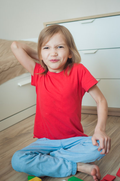 在育婴室里穿着红色t恤的小女孩想扔骰子，很生气图片下载