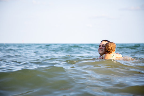 家庭幸福的概念。最好的爸爸。在温暖舒适的海水里，父亲拥抱着一个可爱的蹒跚学步的女儿图片下载