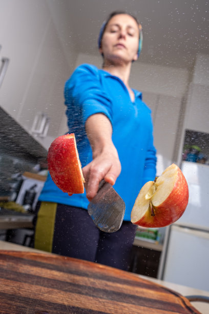 一个白人妇女在家厨房里把红苹果切成两半图片下载