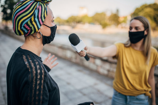 2019冠状病毒大流行期间，在街头接受女记者采访的妇女图片下载