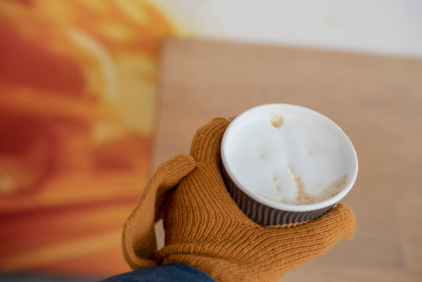 手拿杯子里的热饮，戴上手套。戴着手套，手里拿着咖啡的纸杯。图片下载