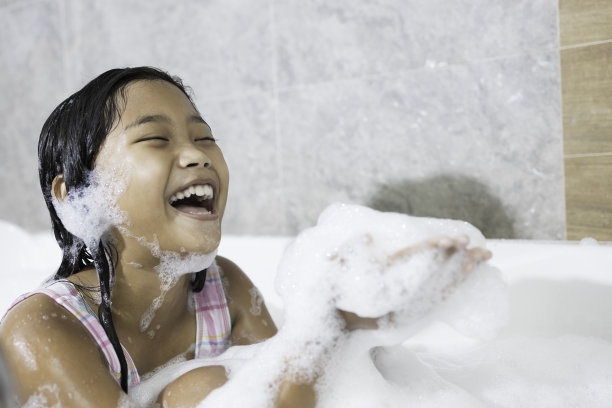 一个亚洲女孩在浴缸里开心地玩肥皂泡。图片下载