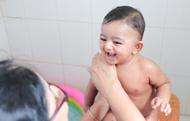 一个可爱的印度无辜的新生儿在愉快的心情与迷人的微笑与水滴在他的身体在淋浴。图片下载