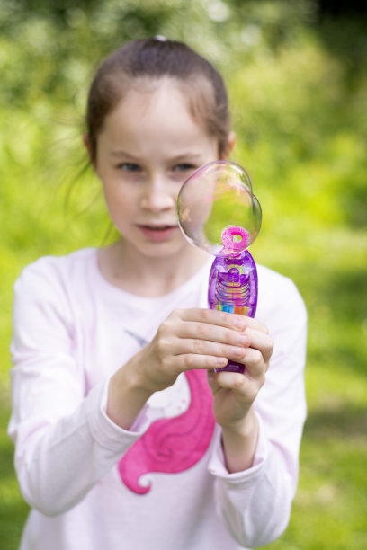 小女孩在室外吹肥皂泡。孩子们的夏季有趣活动。图片下载