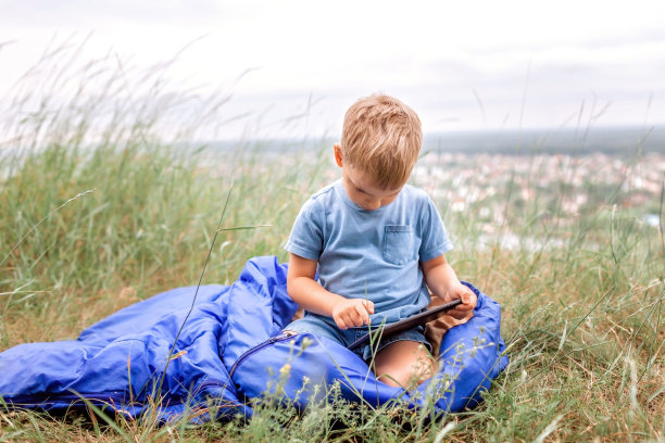 当地假期。睡袋里的男孩在山里和朋友网上聊天图片下载