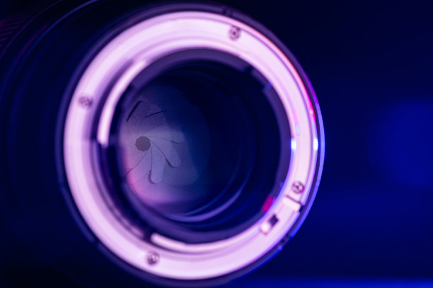 特写相机镜头与背面的刺刀与蓝色光在黑色背景。光学。图片下载