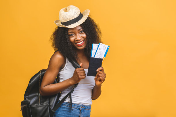 旅行，旅游和度假概念-快乐的年轻非洲裔美国黑人妇女与机票孤立在黄色背景。图片下载